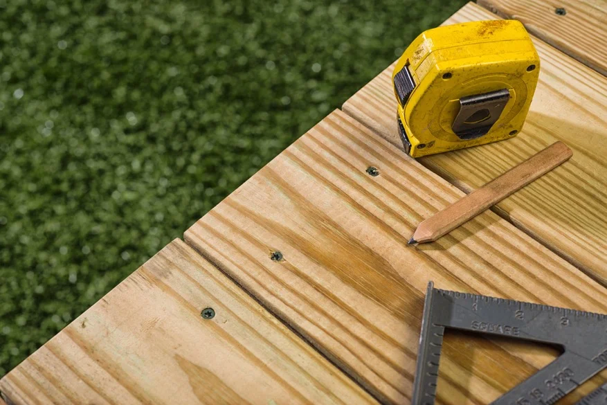 Close up of a deck with a tape measure and other deck building supplies