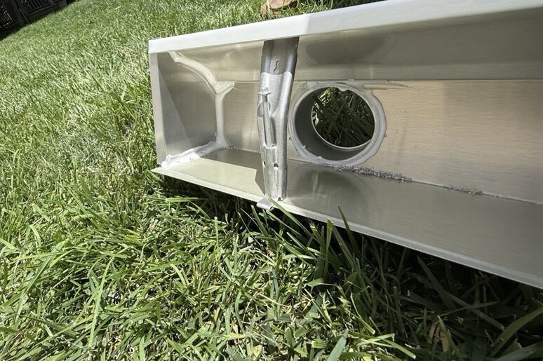 Close-up of an aluminum gutter section with downspout outlet