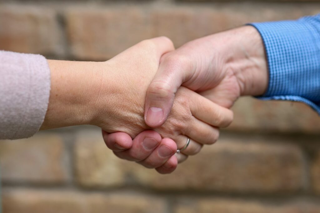 Two people shaking hands in front of a brick wall