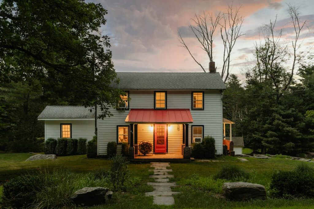 Farmhouse with warm lights on at dusk